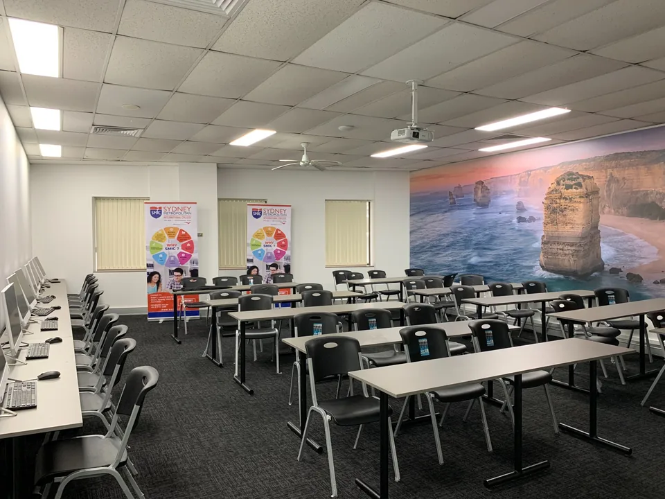 Campus classroom with desktop computers along the wall and tables in the centre
